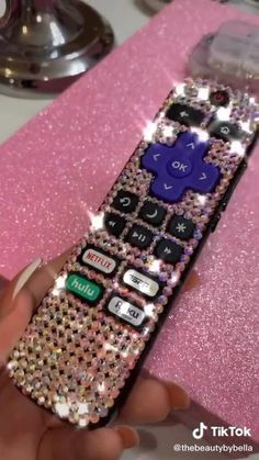 a hand holding a remote control with lots of sparkles on the top of it