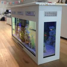 an aquarium in the middle of a room with wooden floors and white walls, on display