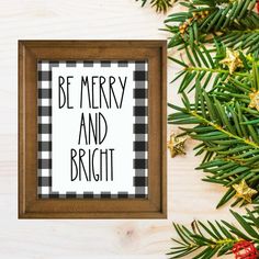 a christmas ornament with the words be merry and bright on it next to pine branches