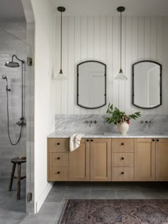 a bathroom with two sinks and mirrors on the wall next to a rug in front of it