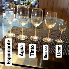 four wine glasses sitting on top of a glass table with labels that say each one is empty