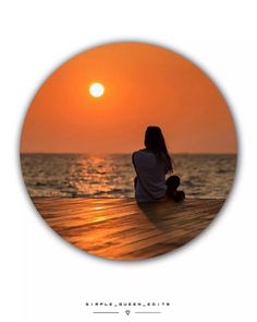 a woman sitting on a dock watching the sunset