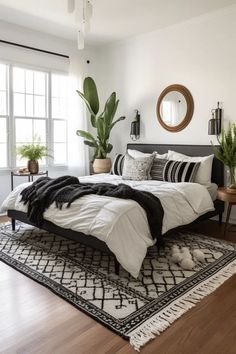 a large bed sitting on top of a wooden floor next to a mirror and potted plants