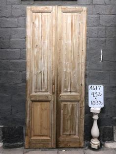 two wooden doors sitting next to each other in front of a brick wall with a sign on it