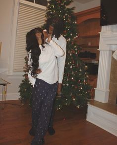 a man and woman standing in front of a christmas tree