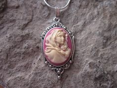 "Beautiful Virgin Mary cradling baby Jesus cameo necklaces I can make matching earrings, brooch and a bracelet also, so please feel free to message me, and I will set up a custom/reserved listing. The cameos are gorgeous, choose from black or pink I do have other colors and styles, so please do browse, I can make any cameo in my shop into this pretty necklace, so browse and message me with a custom order The pretty setting is about 1 1/2\" long, please do see the photo The chain is a 22\" .925 s Pink Adjustable Christmas Jewelry, Collectible Pink Pendant Jewelry, Handmade Pink Jewelry For Christmas, Sterling Silver Cameo Jewelry For Gift, Spiritual Jewelry For Christmas Gift, Personalized Pink Jewelry For Christmas, Personalized Jewelry For Mother's Day Collectible, Red Cameo Necklace For Gift, Pink Cabochon Necklaces For Gift