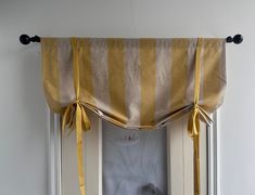 an open window with a yellow and white striped curtain hanging from it's side