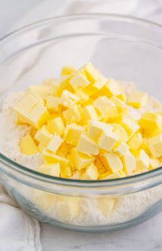 a bowl filled with butter cubes and flour on top of a white table cloth