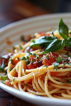 a plate of spaghetti with tomatoes and basil