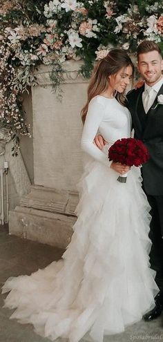 a bride and groom posing for a photo in front of an archway with flowers on it