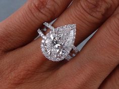 a woman's engagement ring with a pear shaped diamond in the center and pave band