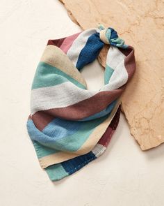 a multicolored scarf laying on top of a piece of wood next to it