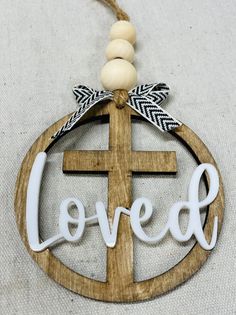 a wooden ornament with the word love on it and a cross hanging from it