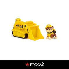 a yellow toy bulldozer next to a small dog on a white background with the words macy's written below it