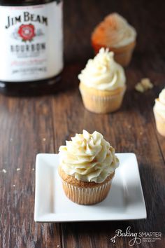 cupcakes with frosting on a white plate next to a bottle of beer