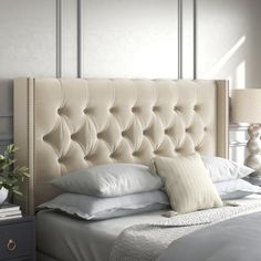 a bed with white sheets and pillows on top of it next to a night stand