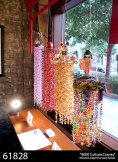 some colorful beads hanging from the ceiling in front of a window with a sign on it