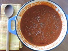 a bowl of chili on a table with a wooden spoon and napkin next to it