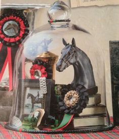 there is a glass cloche with a horse on it and other items under the cloche