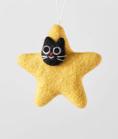 a yellow felt star ornament with a black cat on it's face