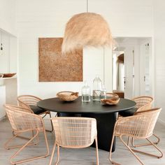 a black table with four chairs around it and a white lamp hanging from the ceiling