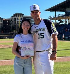 a man standing next to a woman on top of a baseball field