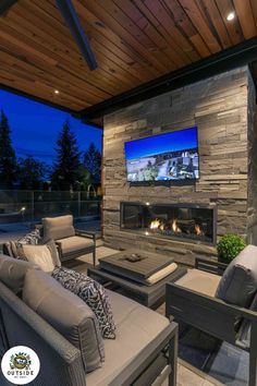 an outdoor living area with couches, chairs and a television mounted on the wall