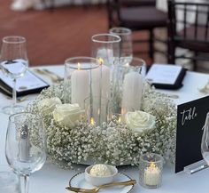 a centerpiece with candles and flowers on a white table cloth at a wedding reception