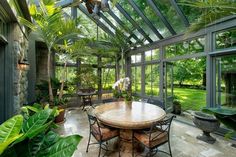 an outdoor dining area with glass walls and lots of greenery