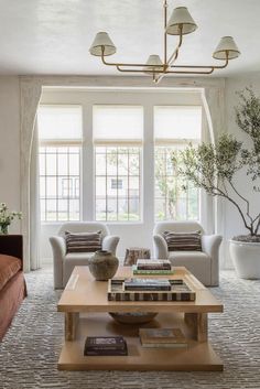 a living room with couches, chairs and a coffee table in front of two windows