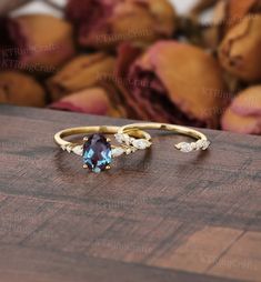 two gold rings with blue and white stones on top of a wooden table next to fruit