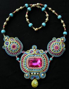 the necklace is adorned with beads, stones and a large pink stone in the center