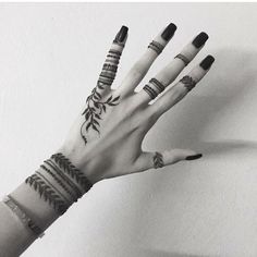 a woman's hand with tattoos and rings on it