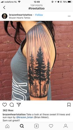 a woman's arm with trees on it and the sun shining through the trees