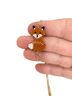 a hand holding a small beaded fox brooch