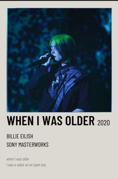 a person with green hair holding a microphone in front of a poster that says, when i was older 2020