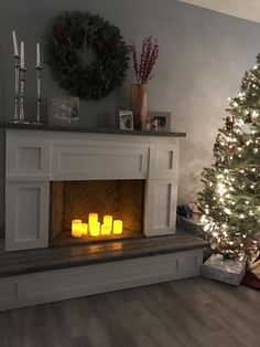 a lit fireplace in a living room next to a christmas tree with candles on it