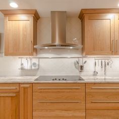 a kitchen with wooden cabinets and stainless steel range hood over the stove, along with white marble counter tops