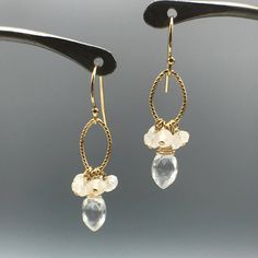 "Sometimes less is more. Our White Topaz and Moonstone earrings need no introduction. They are our \"clear\" favorite, no pun intended! The Marquise-cut White Topaz is deeply faceted to catch every beam of light coming your way. You will be a star with the beautiful Moonstone Rondelles which in a cluster accent the Topaz. Each gemstone is hand wrapped in either 14K Gold-Filled or Sterling Silver wire and added to a textured link and ear wire in coordinating materials. Refreshingly light for wear Handmade Moonstone Wedding Earrings, Drop Moonstone Earrings With Natural Stones, White Gemstone Crystal Dangle Earrings, White Gemstone Dangle Crystal Earrings, Pierced Teardrop Moonstone Earrings, Moonstone Dangle Earrings With Ear Wire, Moonstone Drop Earrings With Ear Wire, Moonstone Crystal Dangle Earrings, Elegant Dangle Gemstone Cluster Earrings