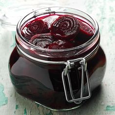 a jar filled with red liquid sitting on top of a table next to a knife