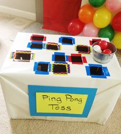 a table that has some kind of box on it with balloons in the background and a sign reading ping ping tass