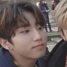 two young men sitting next to each other in front of some stairs with people standing behind them