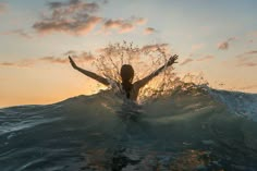 a woman is in the water with her arms out as she stands on top of a wave