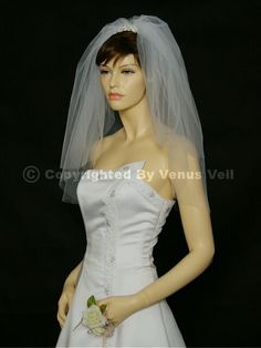 a mannequin wearing a white wedding dress and veil with an orange flower on it