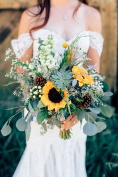 a bride holding a bouquet of sunflowers and greenery