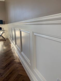 an empty room with hard wood floors and white paneling on the walls, along with a lamp