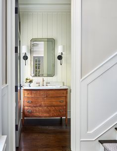 an open door leading to a bathroom with a sink and mirror on the wall above it