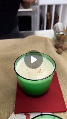 a green bowl filled with liquid sitting on top of a red place mat next to a plate