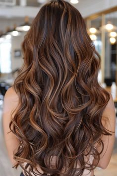 Long, wavy hair with rich brown and caramel highlights in a salon setting. Carmel Red Blonde Balayage, Ash Caramel Highlights, Dark Brown Hair Balayage Auburn Caramel Highlights, Blonde Hair Brown Highlights Caramel, Dark Golden Balayage, Brown Carmel Balayage Hair, Cooper Caramel Hair, Dark Hair Honey Highlights, Carmel Low Lights For Blonde Hair