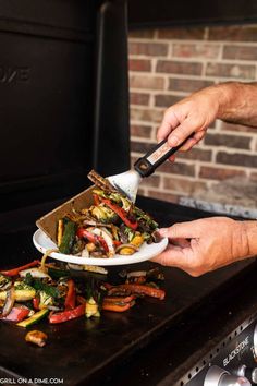 a person using a spatula to stir vegetables on a grill